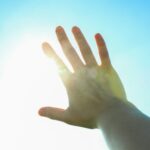 Beautiful blue sky and sun background with woman hand. Wonderful skies