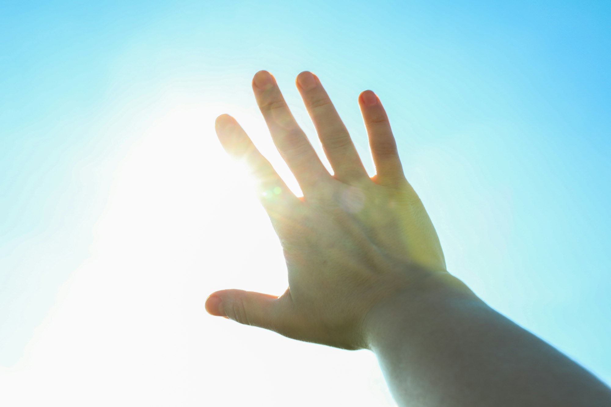 Beautiful blue sky and sun background with woman hand. Wonderful skies