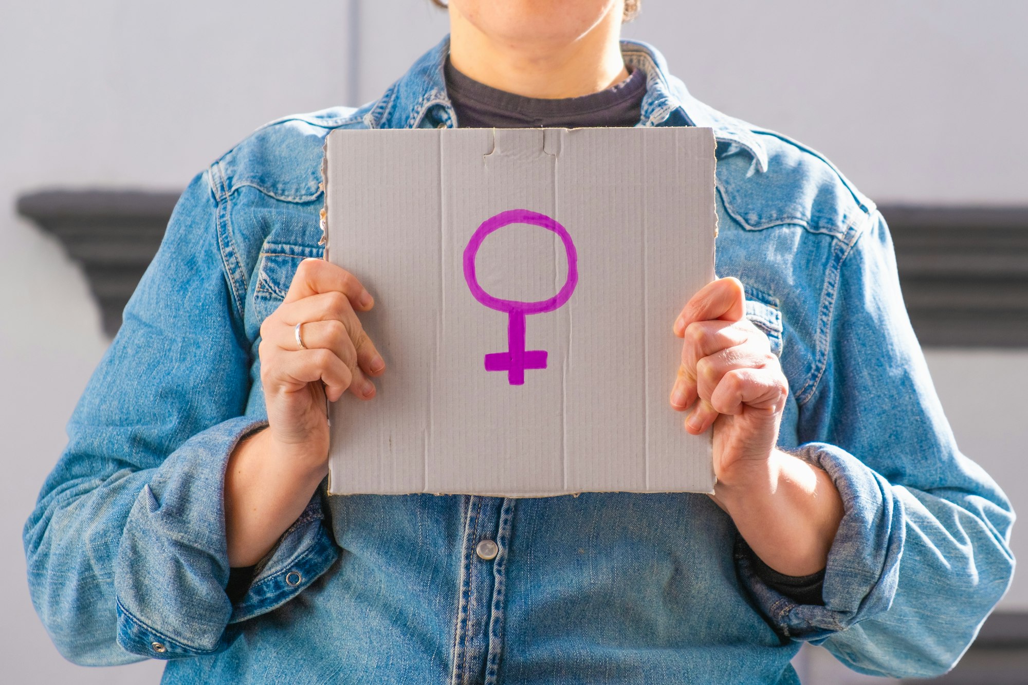 Woman holding cardboard sign with female symbol. Feminist concept, feminism, feminist activist