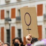 Women hands supporting feminist symbol placard on 8 M demonstration