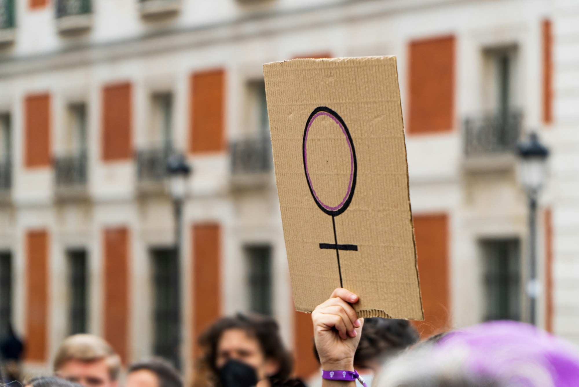 Women hands supporting feminist symbol placard on 8 M demonstration